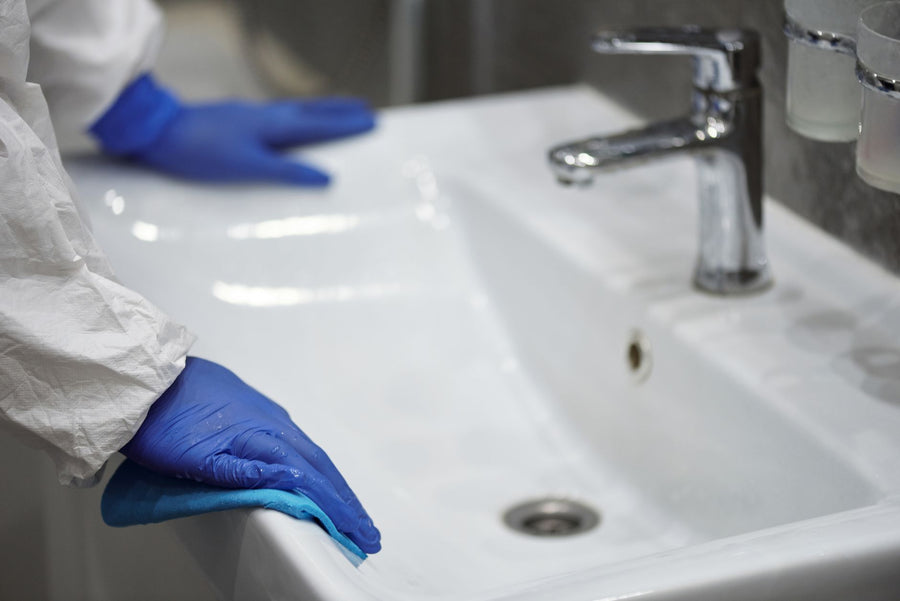 Close-up of a gloved professional cleaning a sink for sanitation