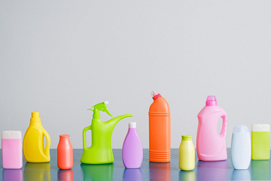 Arrangement of colorful plastic bottles with assorted cleaning products for household placed on table in row against...