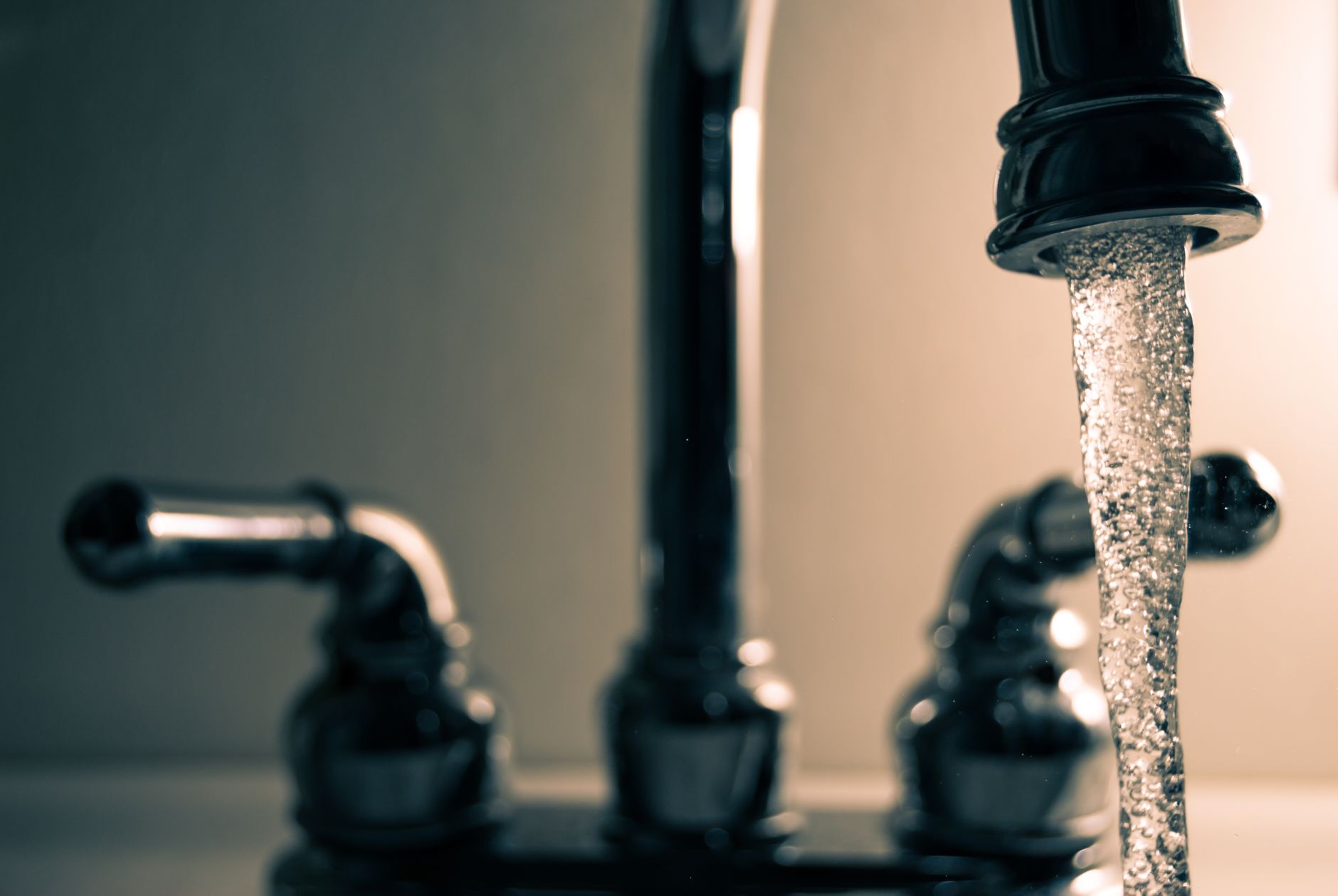 A detailed shot of water flowing from a steel faucet