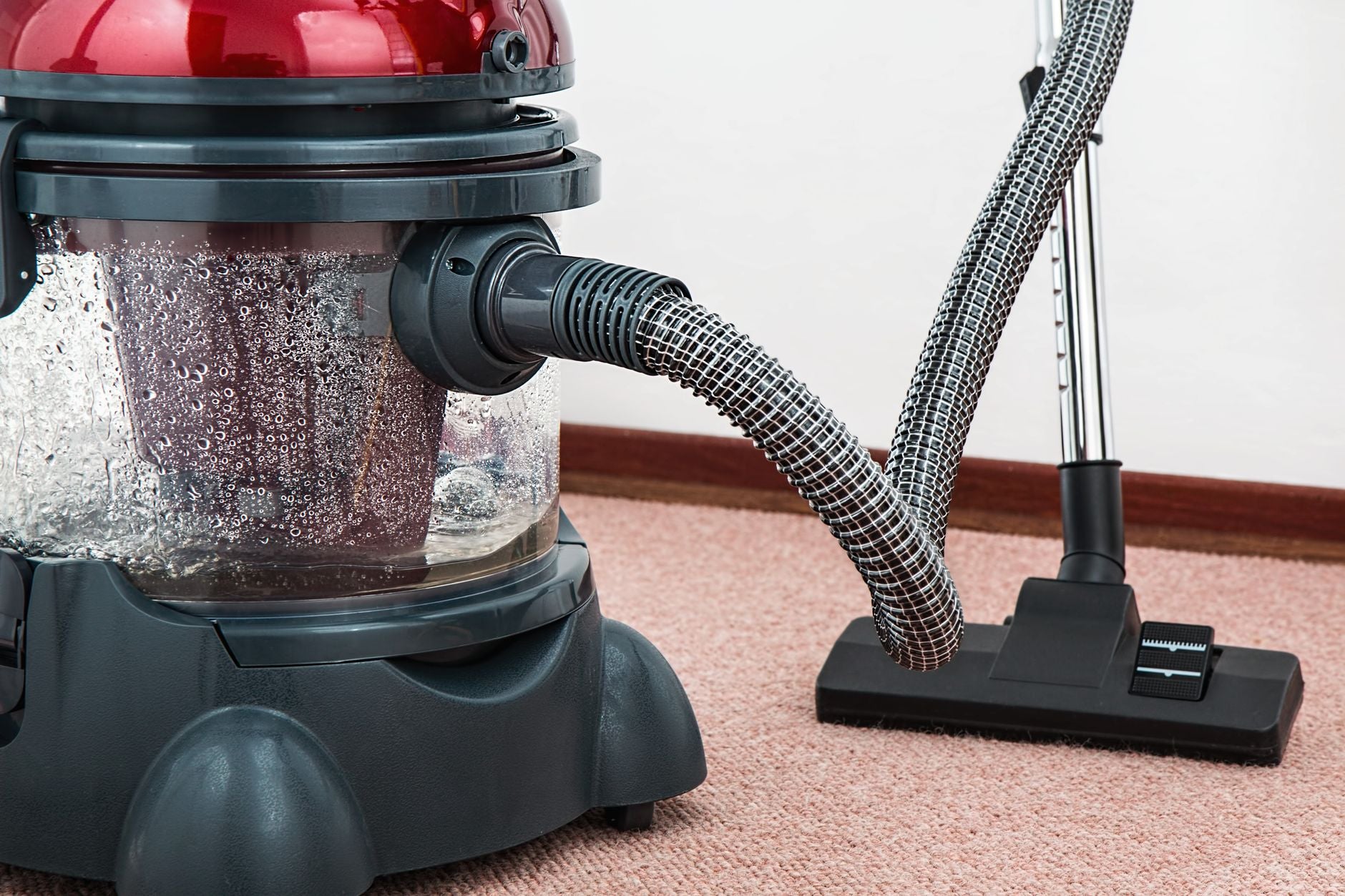 Close-up of a modern vacuum cleaner with water filtration on carpet floor indoors