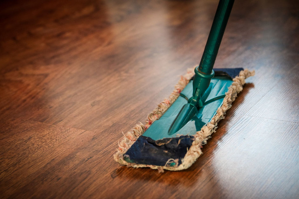 A detailed view of a mop cleaning a wooden floor, showing texture and pattern