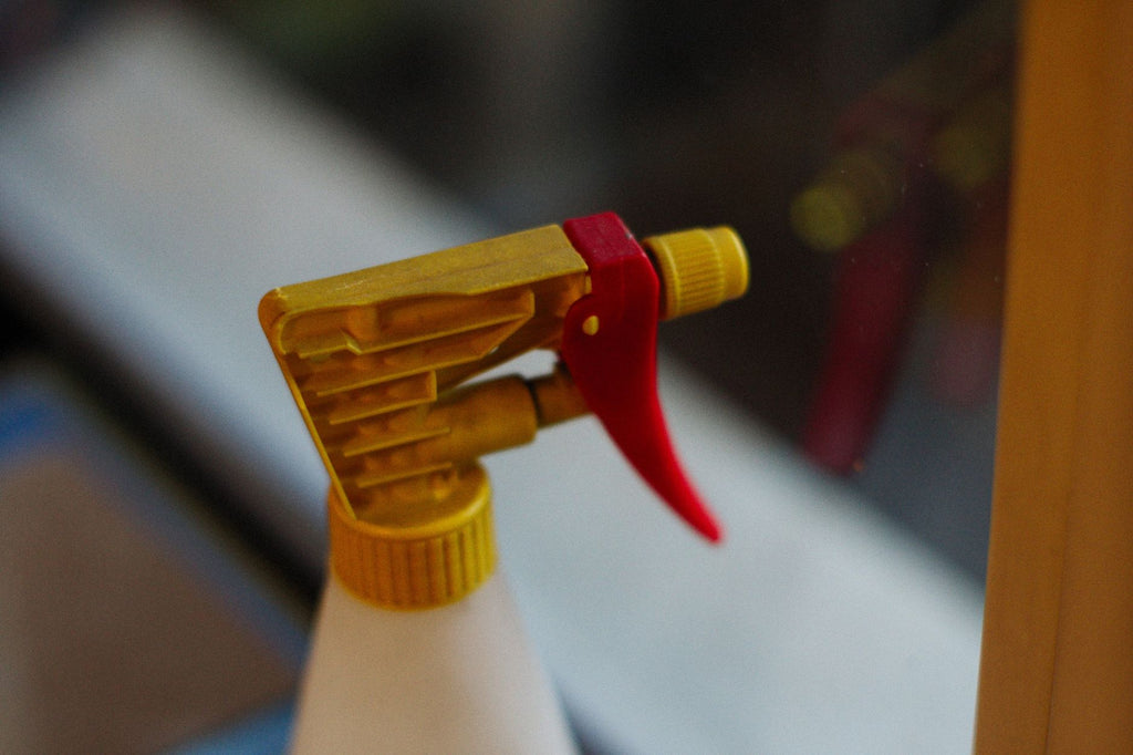 Detailed view of a yellow and red spray bottle nozzle in focus