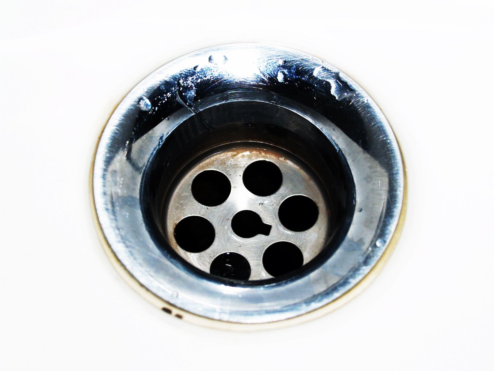 Close-up of a stainless steel sink drain with water droplets around the opening
