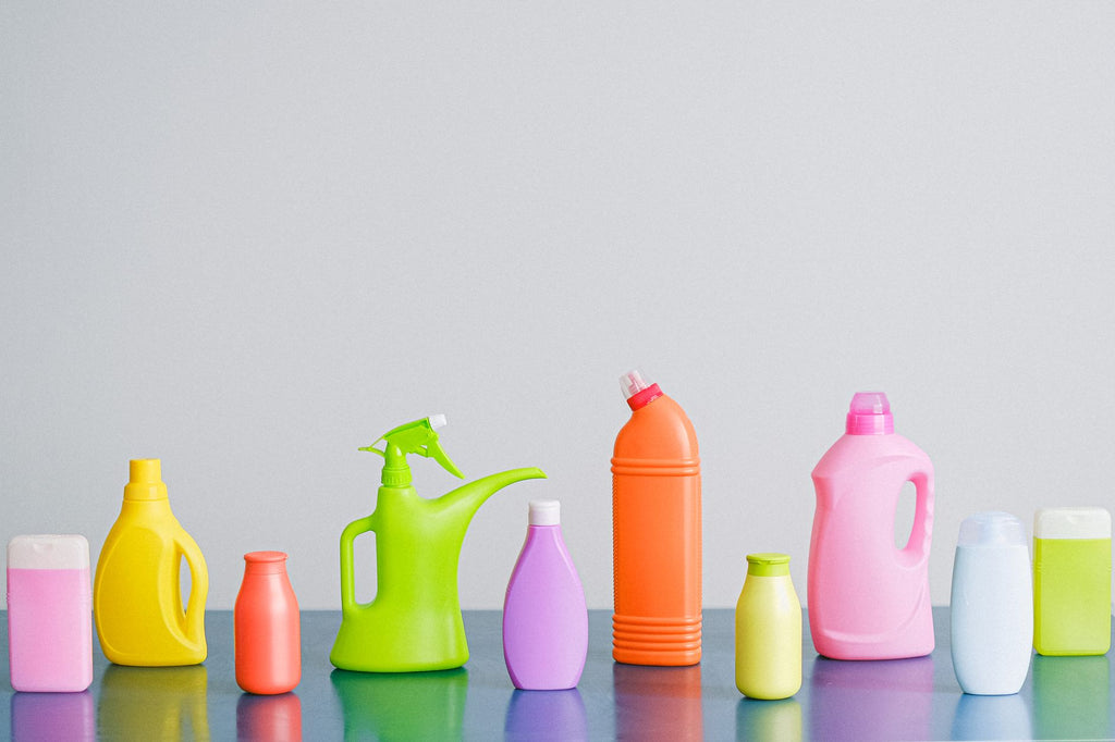 Arrangement of colorful plastic bottles with assorted cleaning products for household placed on table in row against...